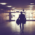 Silhouette of man walking through an empty hallway.
